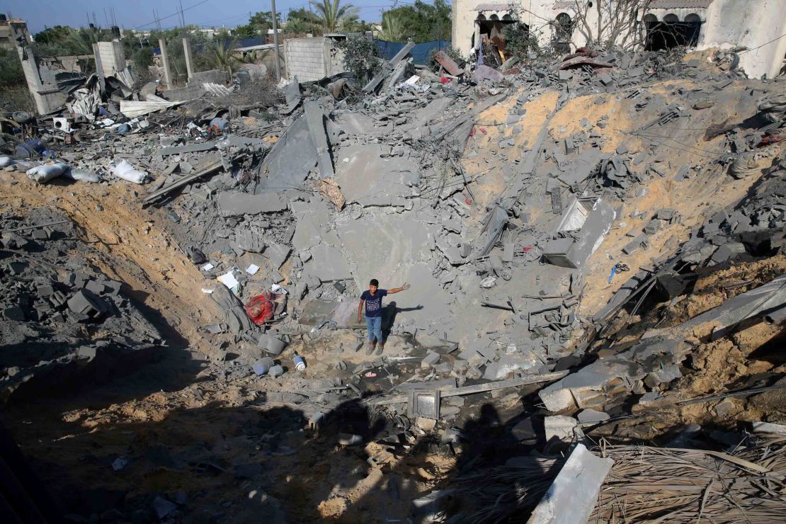 A youth stands in the crater of a destroyed house following overnight Israeli strikes in the Gaza Strip.