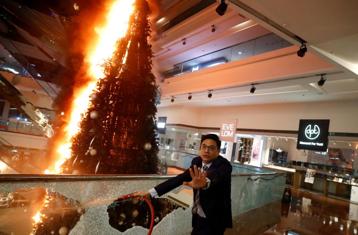 A man tries to extinguish a Christmas tree that protesters set on fire at a mall in Hong Kong on Tuesday, November 12. <a href="https://www.cnn.com/2019/06/09/world/gallery/hong-kong-extradition-protest/index.html" target="_blank">Anti-government protests</a> have been taking place in Hong Kong since early June.