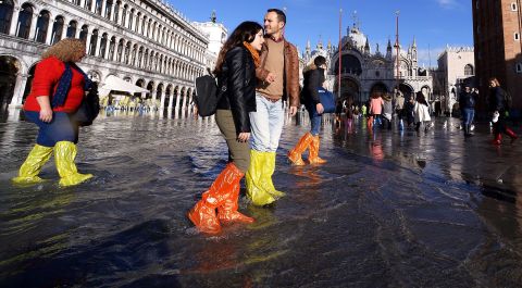 People wearing waterproof shoe covers walk through floodwater on Thursday, November 14, at St. Mark's Square in Venice, Italy.