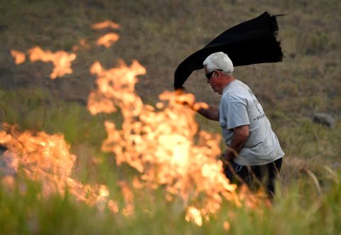 A man uses a wet towel to help put out flames near the town of Taree on November 14.