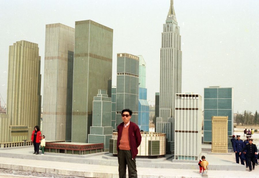 A man poses in front of a replica Manhattan at a Beijing theme park.