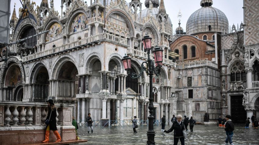 Pedestrians walk across the flooded St. Mark's Square past St. Mark's Basilica after an exceptional overnight "Alta Acqua" high tide water level, on November 13, 2019 in Venice. - Venice was hit by the highest tide in more than 50 years late November 12, with tourists wading through flooded streets to seek shelter as a fierce wind whipped up waves in St. Mark's Square. (Photo by Marco Bertorello / AFP) (Photo by MARCO BERTORELLO/AFP via Getty Images)