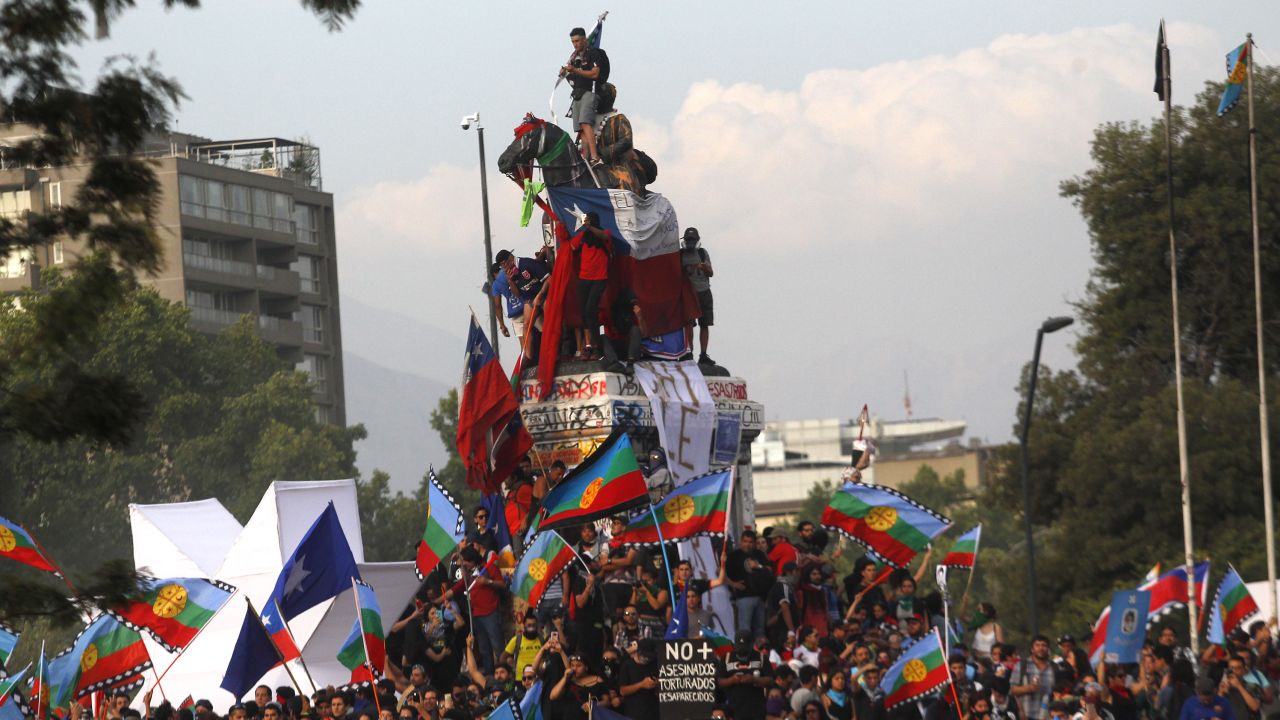 Demonstrators climb on top of a monument in Plaza Italia, Santiago during a protest against Chilean President Sebastian Pinera on November 14, 2019.