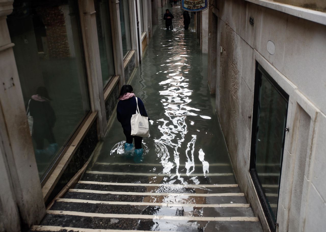 People wade Friday through a flooded Venice alley.