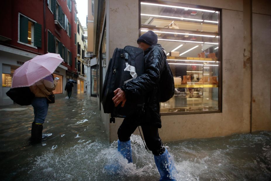 A man carries luggage Friday as he wades through the flood.