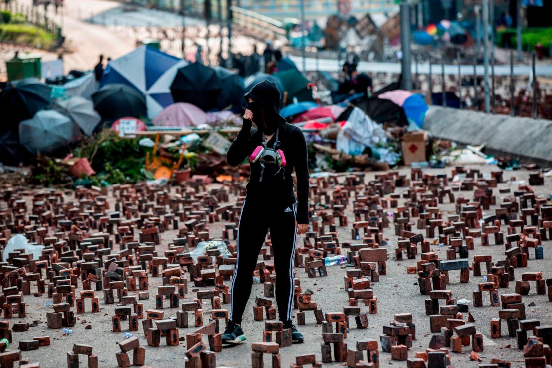 A protester (C) stands amongst bricks placed on a barricaded street outside The Hong Kong Polytechnic University in Hong Kong on November 15, 2019. 