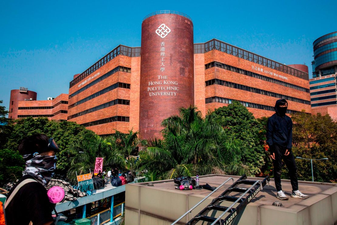 Protesters stand on an overhead walkway next to a barricaded street outside The Hong Kong Polytechnic University in Hong Kong on November 15, 2019.