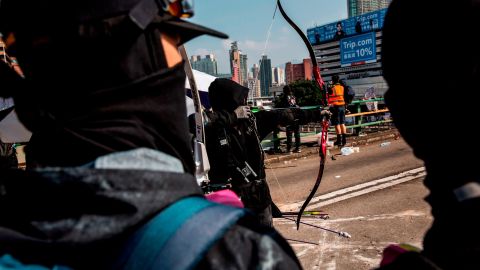 A protester uses a bow and arrow while standing on a barricaded street outside The Hong Kong Polytechnic University in Hong Kong on November 15, 2019. 