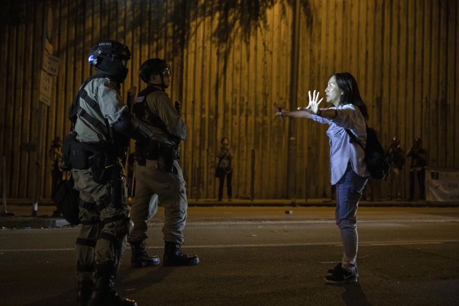 A woman tries to hold back riot police from approaching the Hong Kong University in Hong Kong on Saturday.