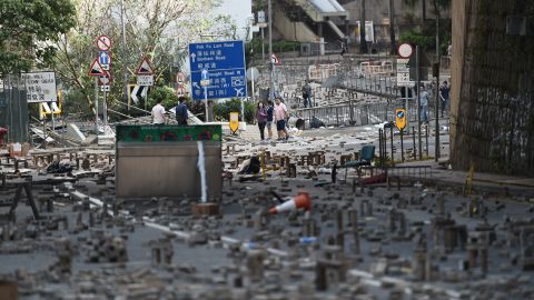 People walk on Saturday, November 16, among bricks laid on a road by protesters near a university in Hong Kong.