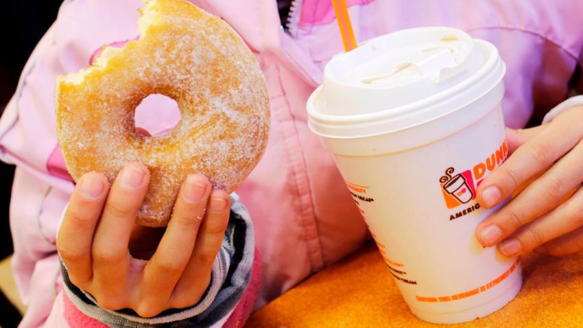 FILE- In this Feb. 14, 2013 file photo, a girl holds a beverage, served in a foam cup, and a donut at a Dunkin' Donuts in New York. The new year means no more plastic foam coffee cups, takeout containers or packing peanuts in most places in the nation's largest city. New York City's long-planned ban took effect on Tuesday, January 1, 2019. (AP Photo/Mark Lennihan, File)