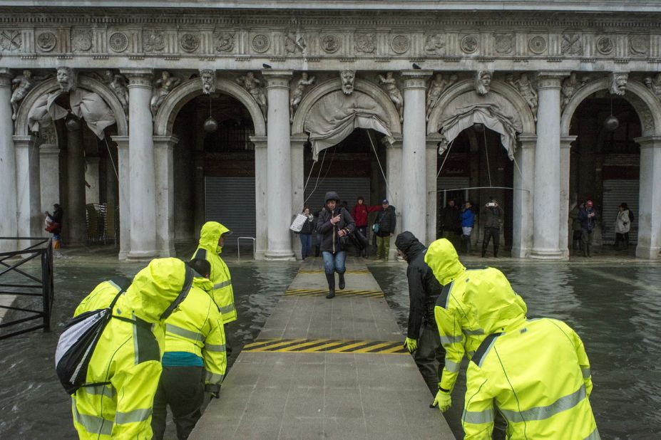 People traverse a provisional footpath built over flood waters on Friday, November 15, in Venice, Italy.