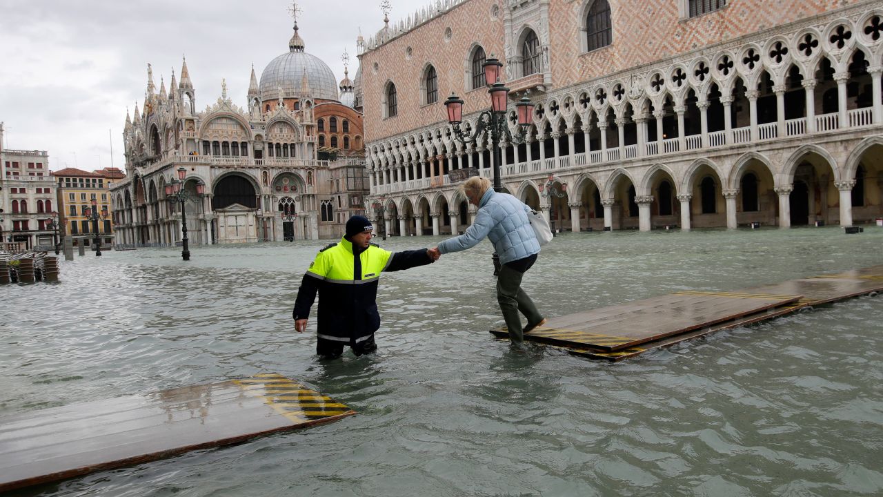 A city worker helps a woman cross a gangway in Venice, Italy, on Sunday, November 17.