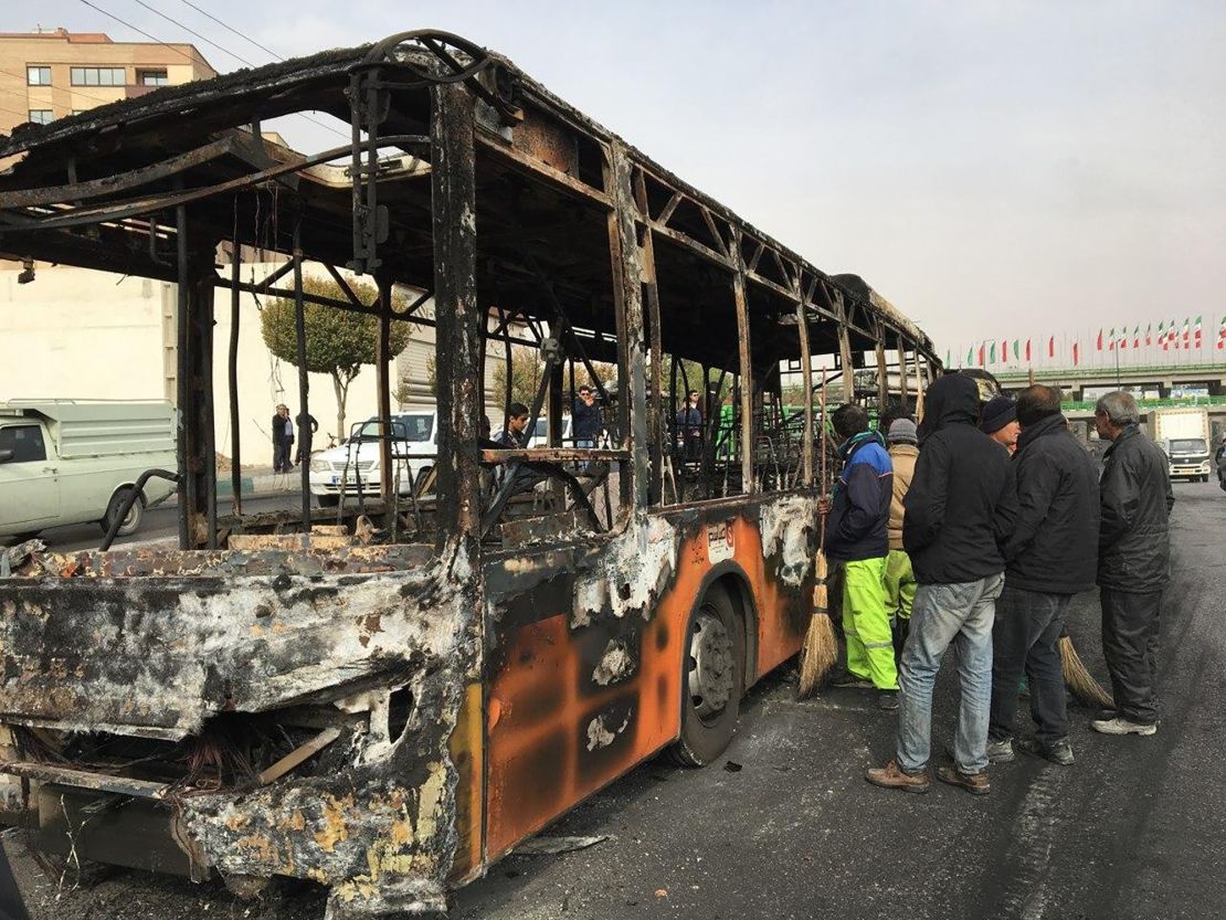 Iranians inspect the wreckage of a bus that was set ablaze by protesters in Isfahan on Sunday.