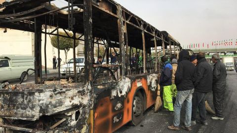 Iranians inspect the wreckage of a bus that was set ablaze by protesters in Isfahan on Sunday.