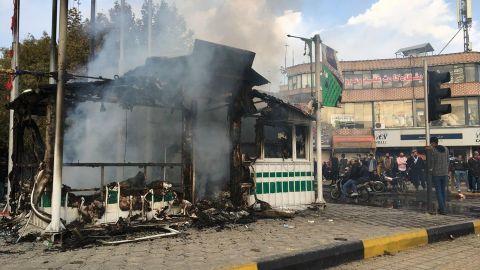 Iranians gather around a charred police station that was set ablaze by protesters on Sunday.
