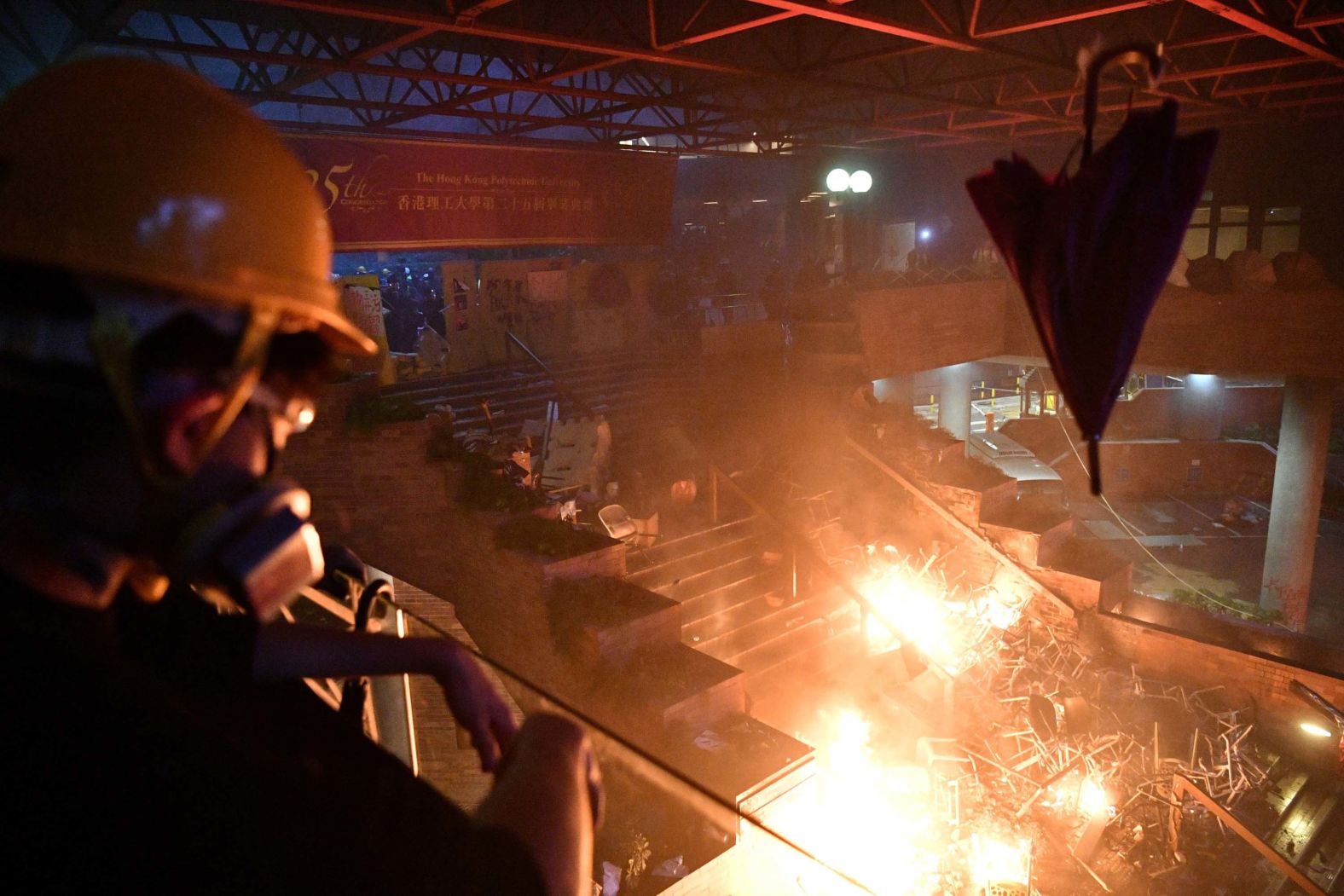 A protester throws an umbrella onto a fire at the barricaded main entrance of Hong Kong Polytechnic University on November 18.