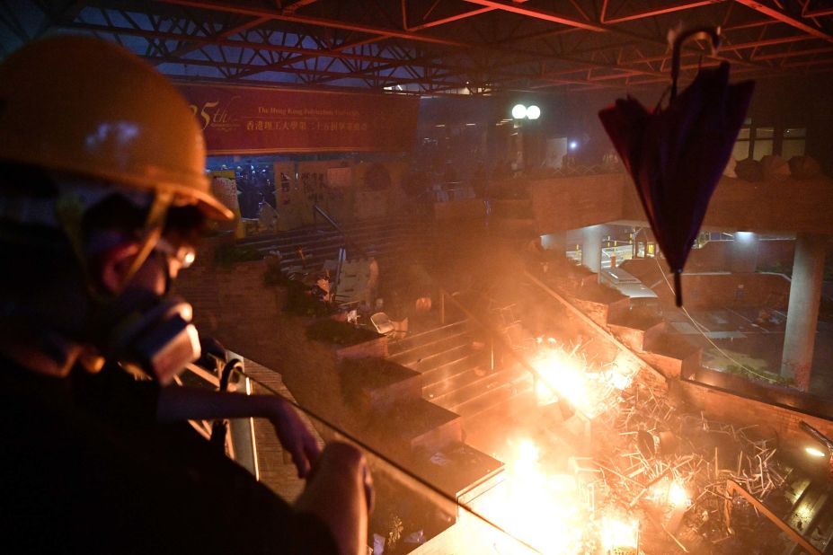 A protester throws an umbrella onto a fire at the barricaded main entrance of Hong Kong Polytechnic University on November 18.