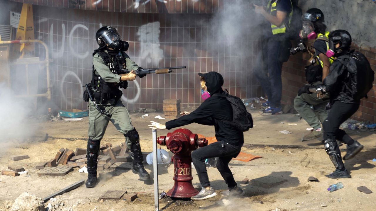 A policeman in riot gear points his weapon as protesters try to flee from the Hong Kong Polytechnic University in Hong Kong, Monday, Nov. 18, 2019. Hong Kong police have swooped in with tear gas and batons as protesters who have taken over the university campus make an apparent last-ditch effort to escape arrest. (AP Photo/Ng Han Guan)