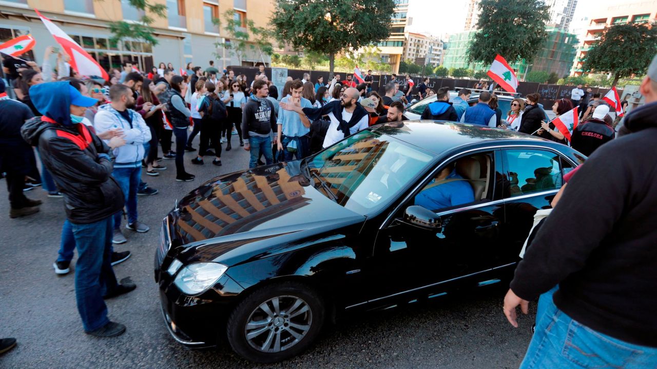 Lebanese protesters block the road before a vehicle in Beirut's downtown district near the country's parliament on November 19, 2019. 