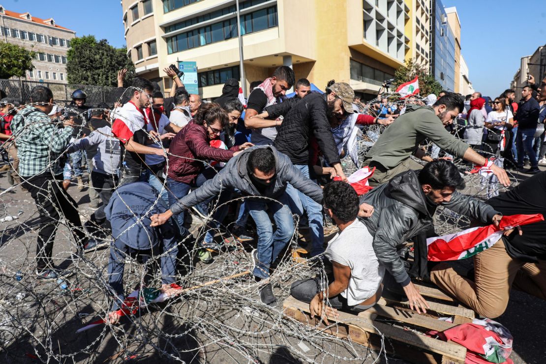 Lebanese protesters flee from security forces after having cut through the security barrier leading to the government palace at Riad al-Solh square on Tuesday.