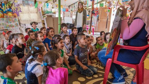 Children listen to a teacher read a "Sesame Street" story in a class at an International Rescue Committee classroom in an informal tented settlement for Syrian refugees.