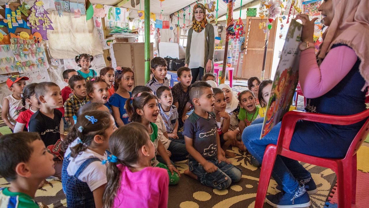 Children listen to a teacher read a "Sesame Street" story in a class at an International Rescue Committee classroom in an informal tented settlement for Syrian refugees.