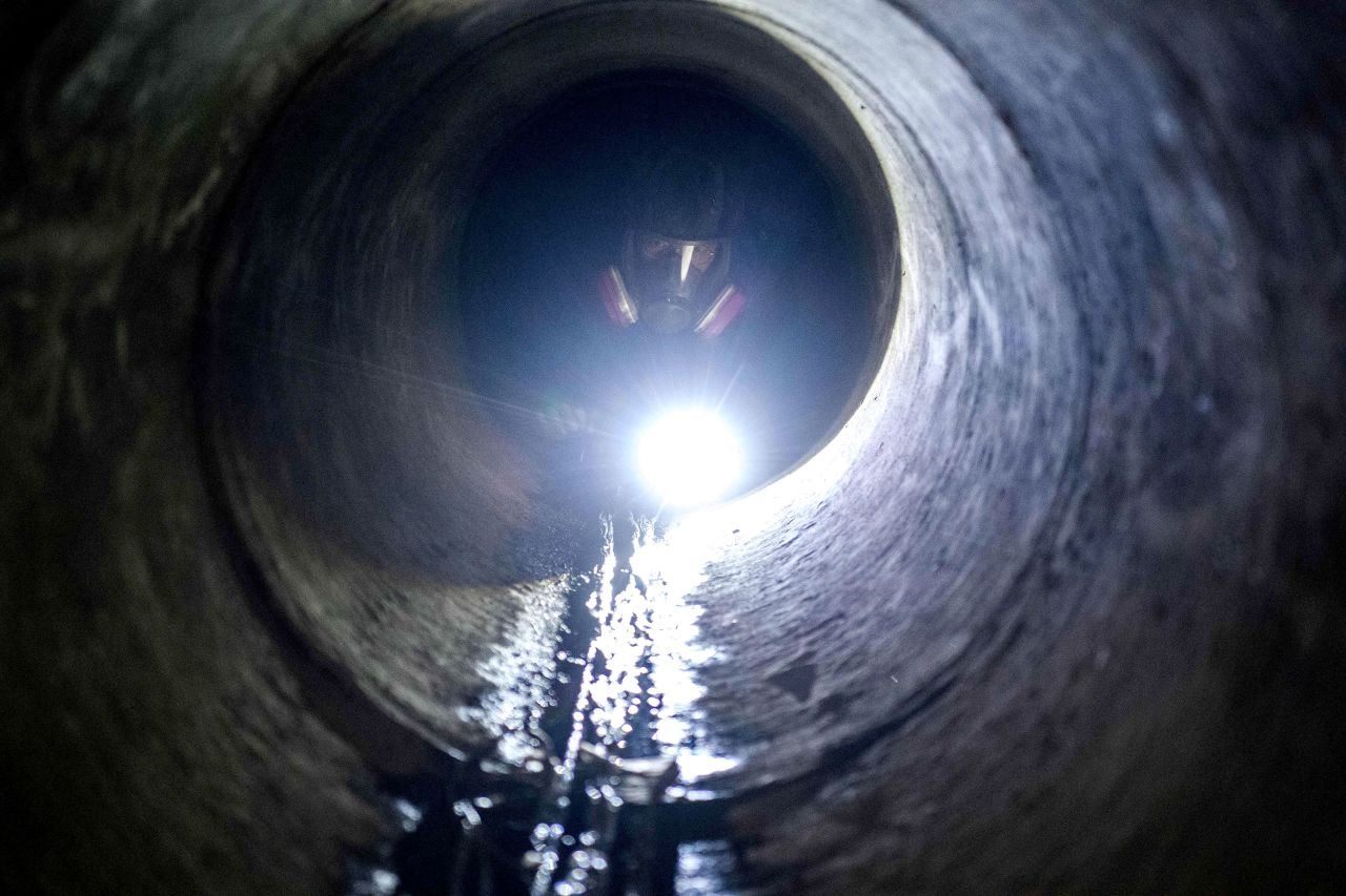 A protester uses a flashlight while crawling through a sewer tunnel to see how wide it is as he and others try to find an escape route from the Hong Kong Polytechnic University on November 19.