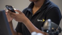 FILE: An employee checks an Apple Inc. iPhone for a customer inside a Sprint Corp. store in San Francisco, California, U.S., on Thursday, May 5, 2016. T-Mobile US Inc. agreed to acquire Sprint Corp. for $26.5 billion in stock, a wager that the carriers can team up to build a next-generation wireless network and get a jump on industry leaders Verizon Communications Inc. and AT&T Inc. Our editors select the best archive images from the two companies. Photographer: David Paul Morris/Bloomberg via Getty Images