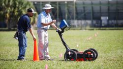 Scott Purcell, a senior geophysicist with GeoView, left, and Mike Wightman, president of GeoView use ground penetrating radar technology to scan a portion of King High School campus in search for Ridgewood Cemetery in Tampa, Florida on Wednesday, October 23, 2019. School officials say ground penetrating radar has located 145 graves on the ground of the high school.  (Octavio Jones/Tampa Bay Times via AP)