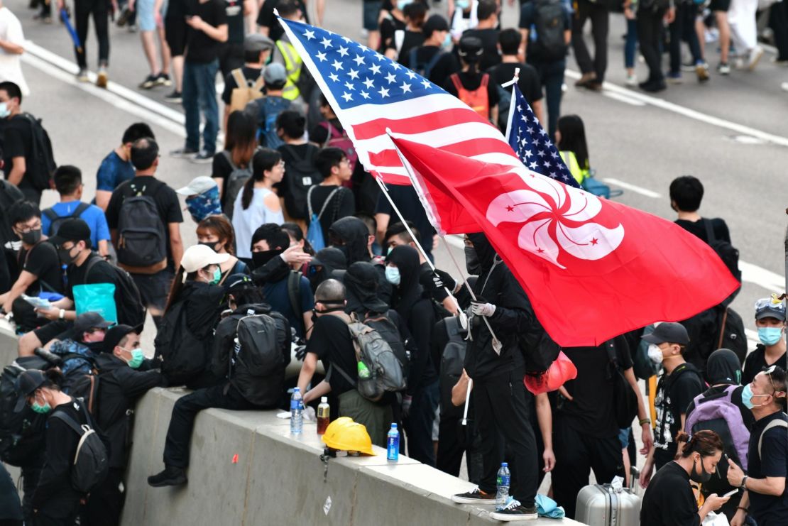 A man waves a US and Hong Kong flag while standing on a divider after he and other protesters occupied Harcourt Road while marching against a controversial extradition bill in Hong Kong on July 21.