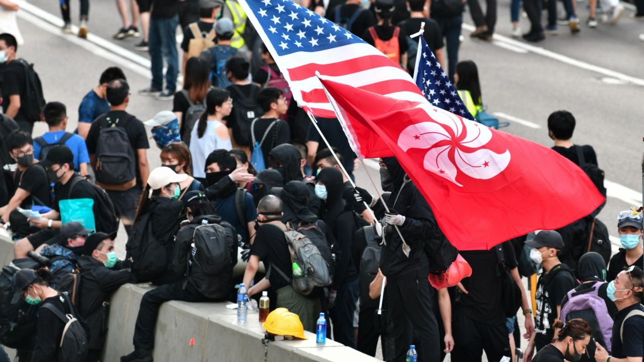 A man waves a US and Hong Kong flag while standing on a divider after he and other protesters occupied Harcourt Road while marching against a controversial extradition bill in Hong Kong on July 21.