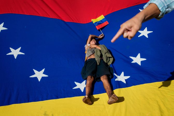 Oliver Duque, a homeless boy, rests on top of a Venezuelan flag during a demonstration called by opposition politician Juan Guaido on Saturday, November 16.