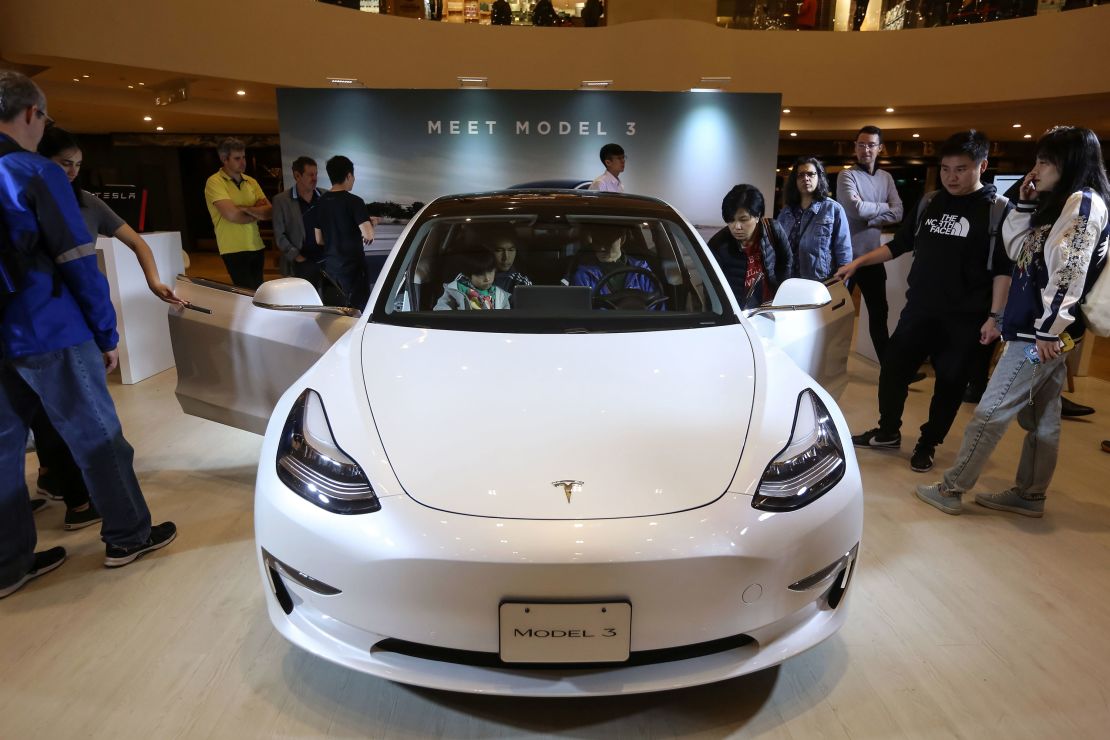 People look at a Tesla Model 3 displayed at a shopping mall in Hong Kong on March 10, 2019. 