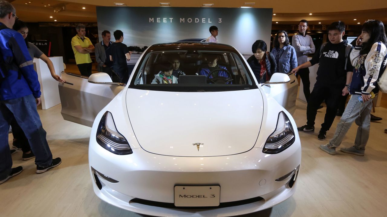 People look at a Tesla Model 3 displayed at a shopping mall in Hong Kong on March 10, 2019. 