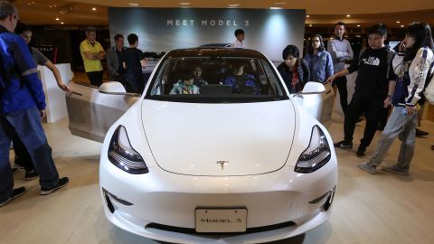 Shoppers in Hong Kong looking at a Tesla Model 3.