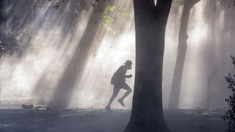 An anti-government demonstrator runs through a tear gas cloud during clashes in Santiago, Chile, on Nov. 19.