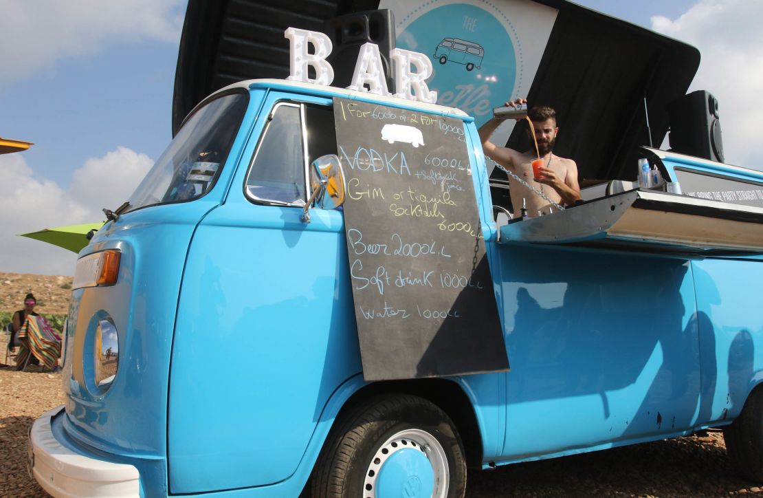 A barman serves drinks from a makeshift bar as Lebanese old Volkswagen car enthusiasts gather at a beach in the southern Lebanese town of Naqoura.