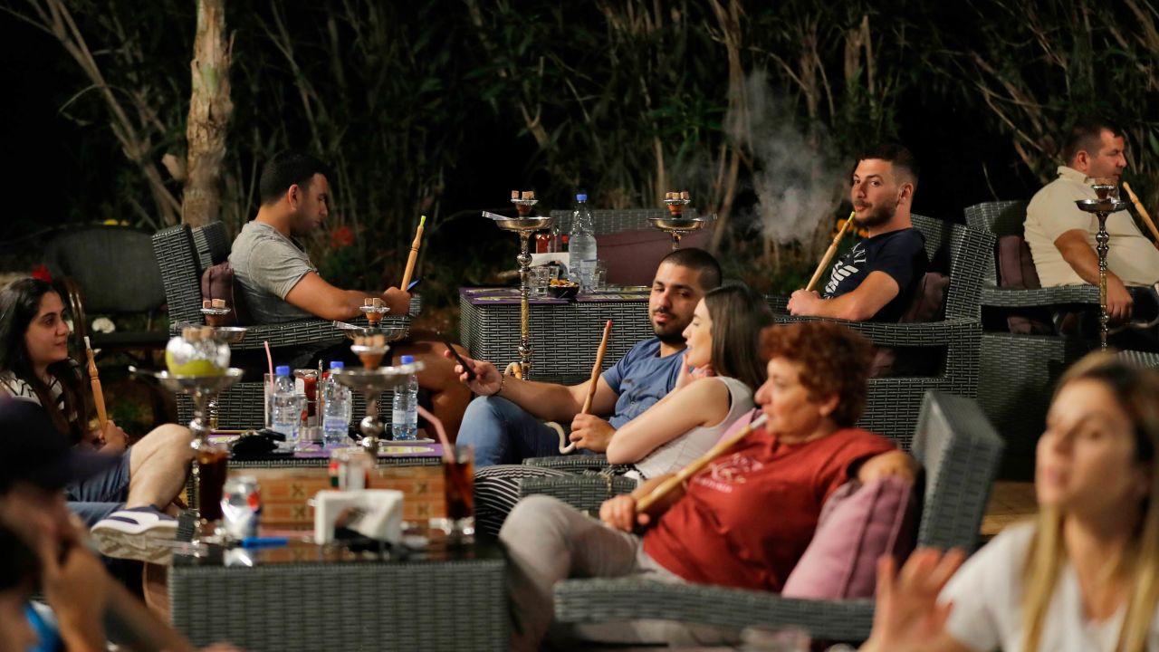 Lebanese people smoke waterpipes at a restaurant in the coastal city of Batroun north of Beirut on May 22, 2019.