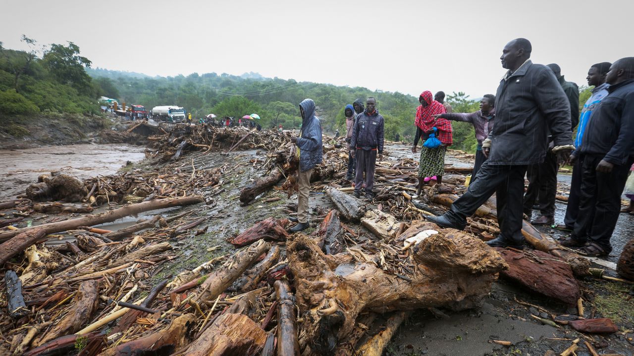 Passengers from stranded vehicles stand next to the debris from floodwaters on the road from Kapenguria in western Kenya Saturday, November 23, 2019. 