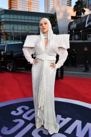 Christina Aguilera struck a bold silhouette in a hooded gown with exaggerated shoulders. 