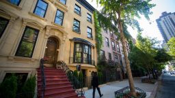A pedestrian walks past a Sotheby's "For Sale" sign displayed outside of a townhouse in New York, U.S., on Monday, June 23, 2014. Americans snapped up previously owned homes in May in the biggest monthly sales gain in almost three years, a sign the residential real estate market is regaining its footing after a stumble early in the year. Photographer: Craig Warga/Bloomberg via Getty Images