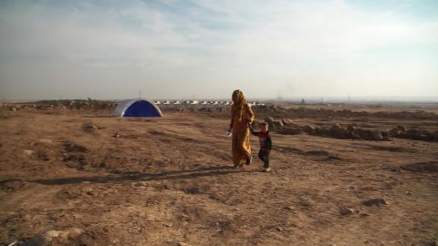 A woman and child walk through a camp housing people forced from their homes by the new conflict.