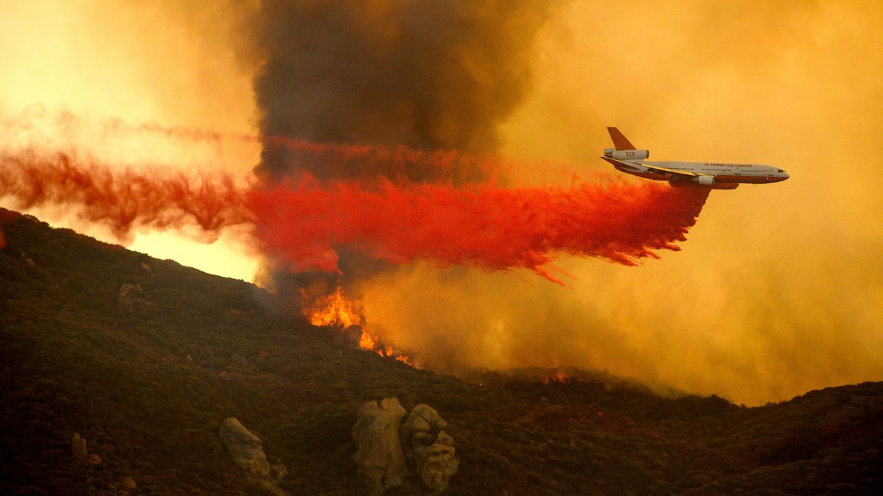 A DC-10 air tanker drops retardant to slow the Cave Fire.