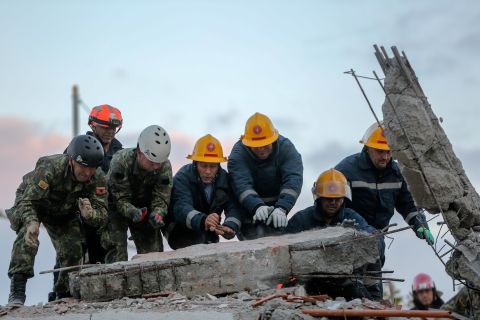 Members of the emergency services work to remove debris from a damaged building in Durres.