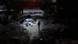 A man walks past debris littering the entrance at the Hong Kong Polytechnic University campus in the Hung Hom district of Hong Kong on November 27, 2019, over a week after police surrounded the building while protesters were still barricaded inside. - Teams at one of Hong Kong's top universities picked through the chaotic aftermath of a violent occupation by protesters for a second day on November 27 as the school searches for elusive holdouts -- and a way forward for a devastated institution. (Photo by Anthony WALLACE / AFP) (Photo by ANTHONY WALLACE/AFP via Getty Images)