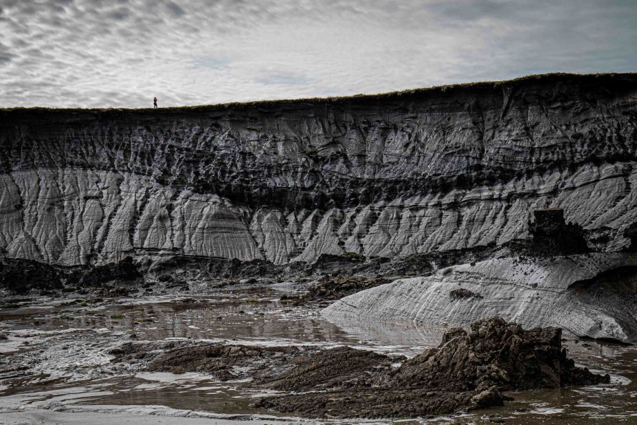 <strong>Qikiqtaruk-Herschel Island, Canada:</strong> A human silhouette is dwarfed by the size of a retrogressive thaw slump on Qikiqtaruk-Herschel Island in Canada. The shifts resulting from these slumps can echo through the whole ecosystem. This photo was taken on an expedition supported by the National Geographic Society. 