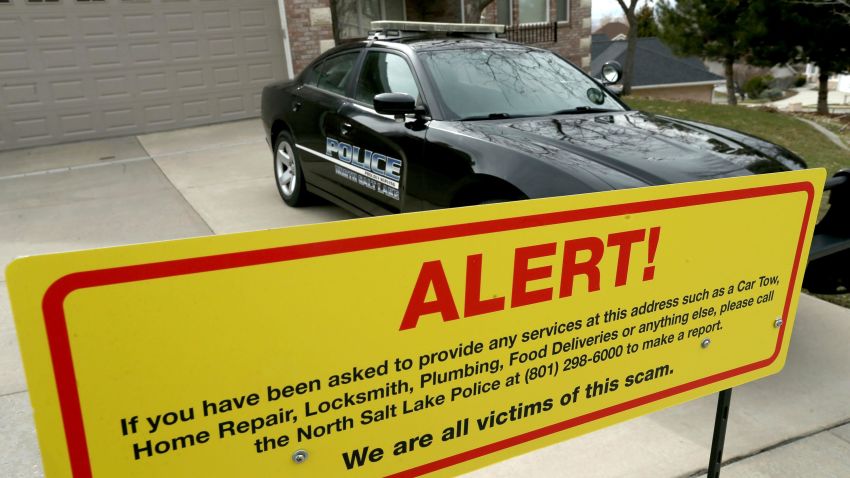 This March 21, 2019 file photo shows a warning sign and a police officer's vehicle at Walt Gilmore's home in North Salt Lake, Utah. U.S. prosecutors arrested Loren Okamura, a Hawaii man, on November 22, who they accuse of sending hundreds of unwanted service providers to the Utah home, including plumbers and prostitutes. It's unknown why the Gilmores were targeted or what if any relationship exists between Okamura and the family.