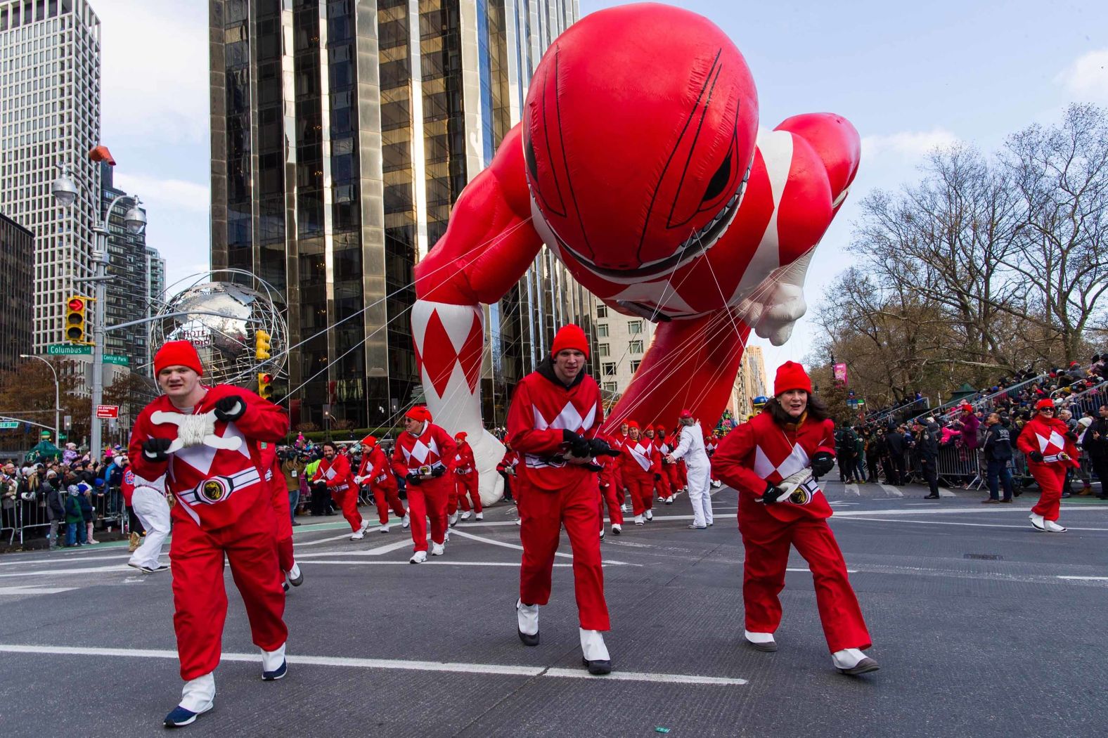 Parade volunteers fight with winds as they hold a Power Rangers balloon on Columbus Circle.