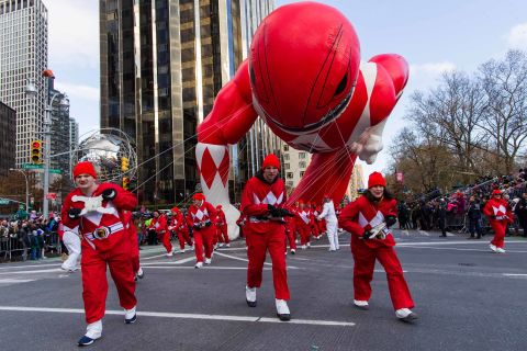 Parade volunteers fight with winds as they hold a Power Rangers balloon on Columbus Circle.